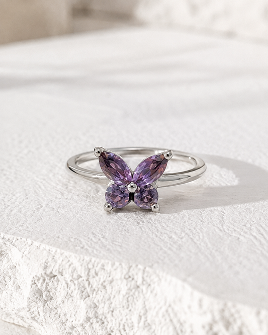 A silver ring with a purple gemstone in the shape of a butterfly.