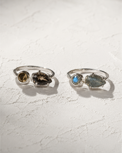 Two silver rings with gemstones are displayed on a white surface.