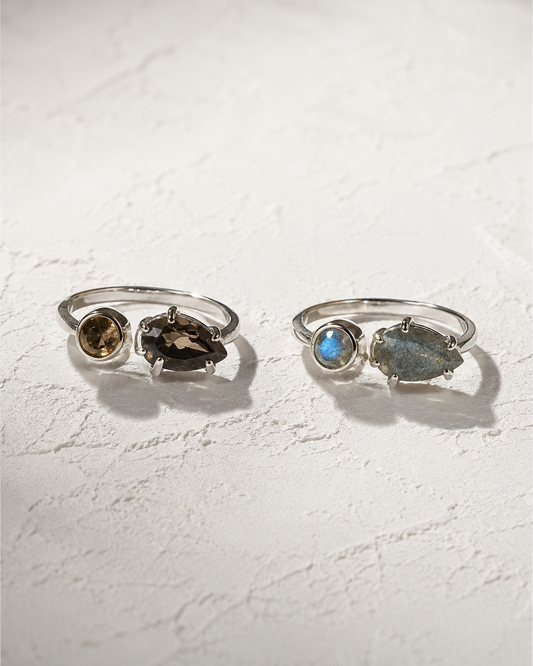 Two silver rings with gemstones are displayed on a white surface.