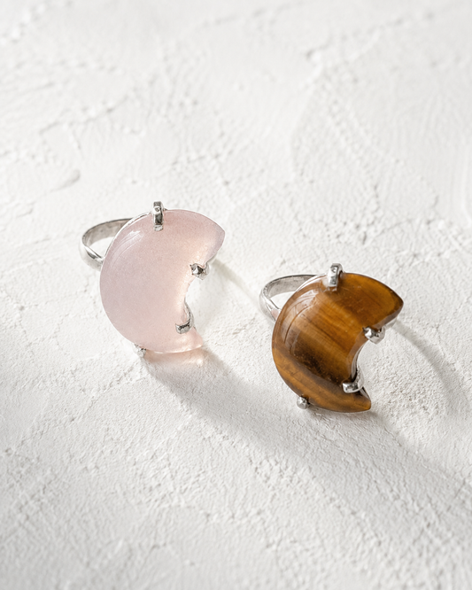 Two rings with moon-shaped stones are displayed on a white surface.