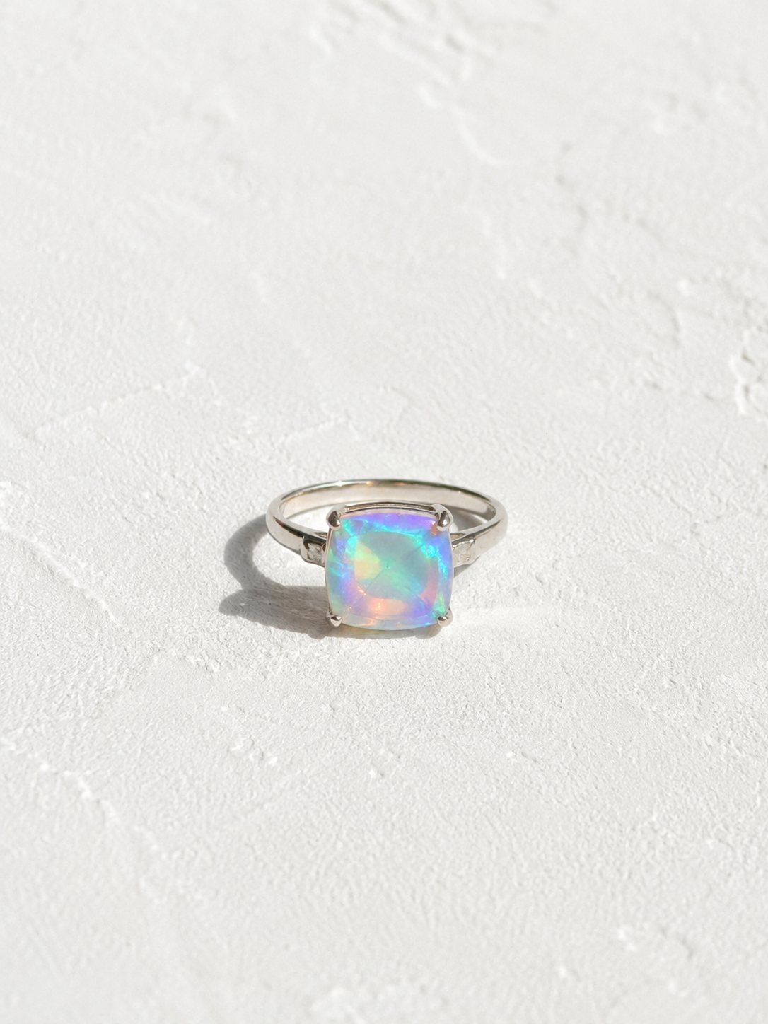 A silver ring with a large, multicolored opal gemstone set in the center.