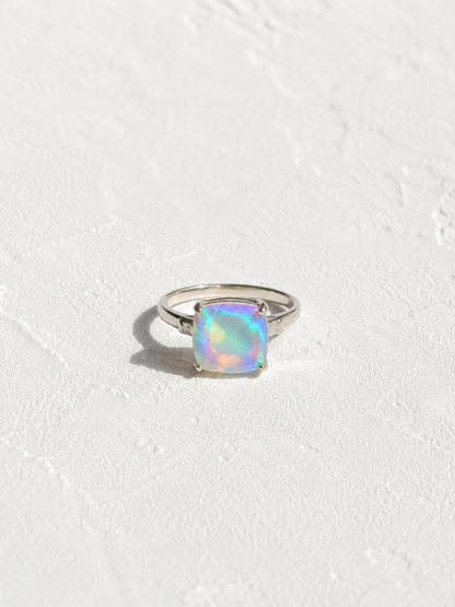 A silver ring with a large, multicolored opal gemstone set in the center.