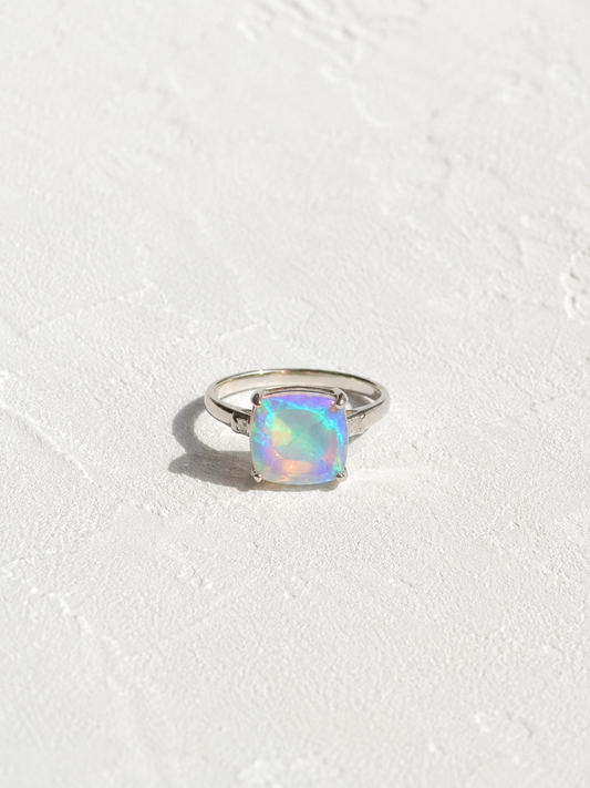 A silver ring with a large, multicolored opal gemstone set in the center.