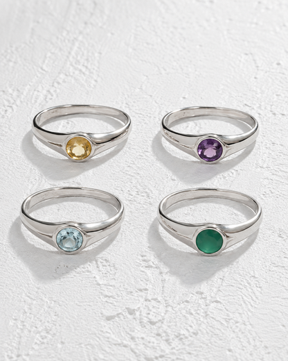 four silver rings with gemstones, each with a different colored gemstone.