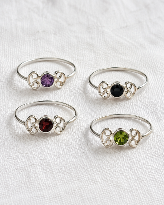 four silver rings with gemstones, each with a unique design and color.